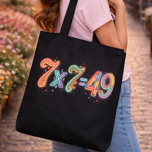 Könnte beinhalten: Schwarze Tragetasche mit der Gleichung "7 x 7 = 49" in farbenfrohen Neonbuchstaben. Das Design weist orange, grüne, blaue und rosa Farbtöne mit Sternakzenten auf. Die Tasche hat schwarze Griffe.