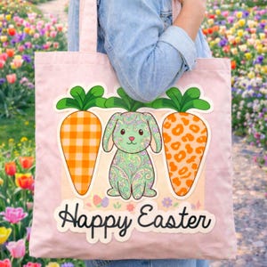 Pode incluir: Uma sacola rosa com um coelho de desenho animado e duas cenouras. O coelho é verde com um design paisley, e as cenouras têm padrões laranja. As palavras "Happy Easter" estão escritas em uma fonte cursiva.