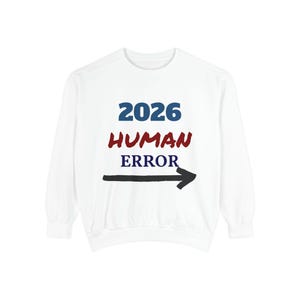May include: White sweatshirt featuring the text "2026 HUMAN ERROR" in blue and red, with a black arrow pointing right. The garment has long sleeves and a crew neck.
