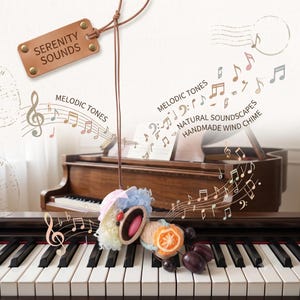 May include: A handmade wind chime featuring a small doll with blue and white hair, a pink hat, and an orange slice accent, suspended by a brown cord from a leather tag labelled SERENITY SOUNDS, with musical note graphics and text overlays.