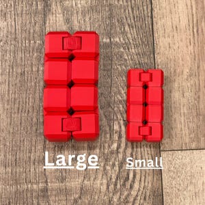 Puede incluir: Dos cubos infinitos rojos, uno grande y otro pequeño, se muestran sobre una superficie de madera. El cubo más grande tiene seis bloques conectados, el más pequeño tiene tres. Las palabras "Large" y "Small" están escritas debajo.