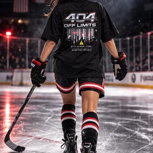 May include: A person wearing a black t-shirt with the text "404 OFF LIMITS" and barcode design, black shorts with red and white stripes, and black and red hockey gloves. The person is on an ice rink, holding a hockey stick.