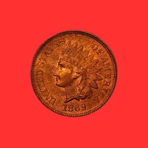 May include: A copper-colored 1869 Indian Head penny coin. The coin features a profile of a Native American in a feathered headdress, surrounded by the words "UNITED STATES OF AMERICA". The year "1869" is visible below the profile.