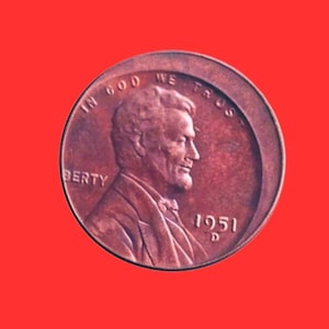 Puede incluir: Una moneda de un centavo estadounidense de 1951, de color cobre. El anverso presenta el perfil de un hombre, la palabra "LIBERTY" y la frase "IN GOD WE TRUST". También es visible el año "1951".