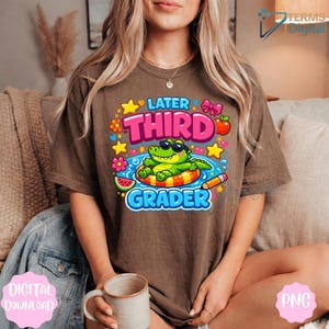 Könnte beinhalten: Braunes T-Shirt mit einem farbenfrohen Aufdruck, der ein Cartoon-Alligator mit Sonnenbrille auf einem Schwimmring zeigt. Der Text lautet "Later Third Grader" mit Sternen, Blumen, einer Wassermelone und einem Bleistift.