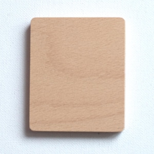 May include: A square, light-coloured wooden block with rounded corners. The wood grain is visible, and the block is set against a white background. The block appears to be a craft supply or a component for a larger project.
