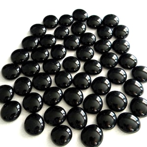 May include: A large pile of black glass pebbles, also known as marbles or gems, for use in crafts, home decor, or vase fillers.