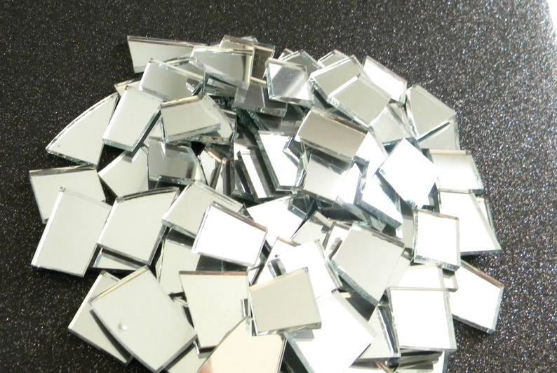 May include: A pile of small, square, silver mirror tiles. The tiles are arranged in a random pattern and are all the same size.