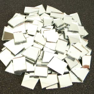 May include: A pile of small, square, silver mirror tiles. The tiles are arranged in a random pattern and are all the same size.