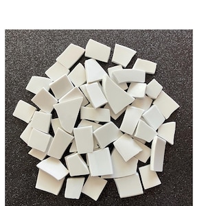 May include: A pile of white ceramic tile pieces, some are square, some are rectangular, and some are curved. The tiles are arranged in a random pattern.