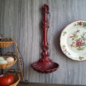 May include: A white ceramic mug with a black handle and the text "But First, Coffee" in a bold, black font. The mug is set against a blurred background, suggesting a cozy setting.