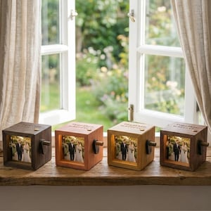 Puede incluir: Cuatro cubos de fotos de madera con una foto de boda iluminada en su interior. Cada cubo tiene un tono de madera diferente, desde marrón oscuro hasta roble claro. El texto "Together wherever" está grabado en la parte superior y una pequeña manivela en el lateral.