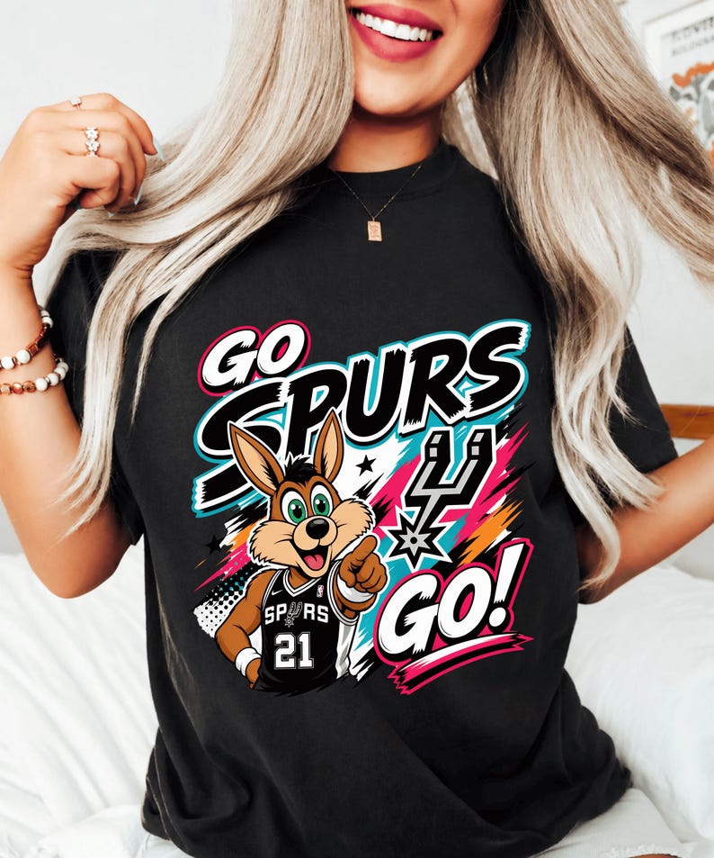 May include: Black t-shirt with a cartoon jackrabbit wearing a Spurs jersey, the text "GO SPURS GO!" in white, teal, and pink. The jackrabbit is pointing with its right hand.