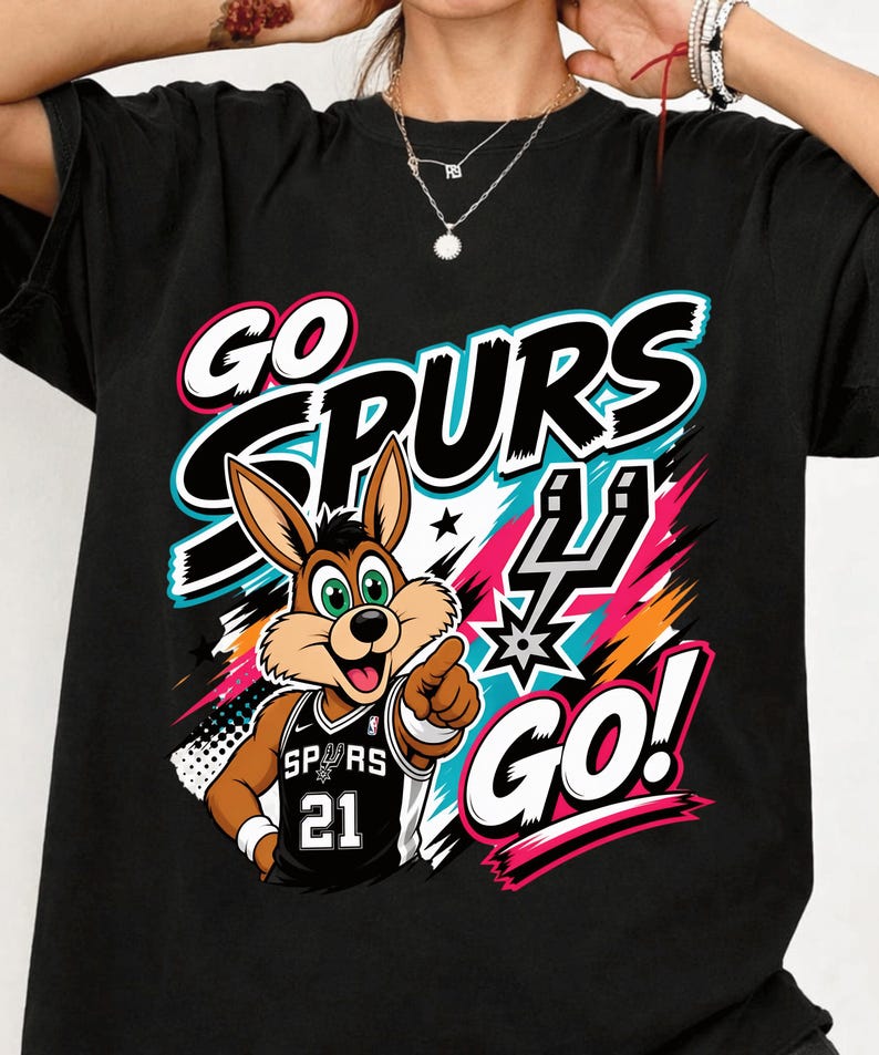 May include: Black t-shirt featuring a cartoon jackrabbit wearing a Spurs jersey with the number 21. The shirt has the words "GO SPURS GO!" in white, black, pink, and teal. A colorful graphic design is behind the jackrabbit.