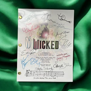 Puede incluir: Un guion blanco con el título "WICKED" y firmas. El guion presenta una imagen promocional del musical y texto, incluidos los nombres de los guionistas y la frase "No one mourns the wicked!"