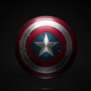 May include: A round shield with a red, white, and blue color scheme. The shield features a white star on a blue center, surrounded by concentric red and white bands. The shield has a distressed, battle-worn appearance.