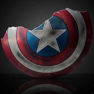 Puede incluir: Un escudo de Capit&aacute;n Am&eacute;rica da&ntilde;ado, con un centro azul con una estrella blanca, rodeado de rayas rojas y blancas. El escudo muestra signos de desgaste, con una parte importante faltante, d&aacute;ndole un aspecto desgastado.