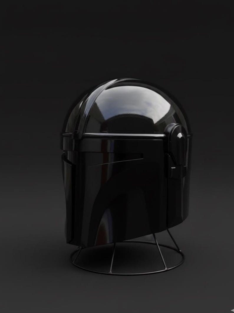 May include: A shiny black helmet, possibly for costume or display purposes, is set against a dark backdrop. The helmet has a smooth, reflective finish and is held up by a slender, wire stand. The design hints at a futuristic or science fiction aesthetic.