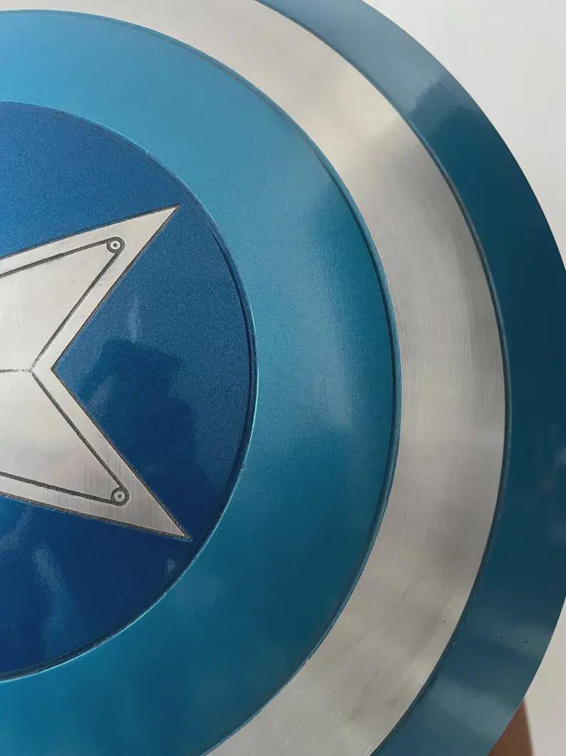 May include: A close-up of a blue and silver shield with a white star in the center. The shield has a circular design with concentric rings of blue and silver. The star has a silver outline and is centered on a dark blue background.