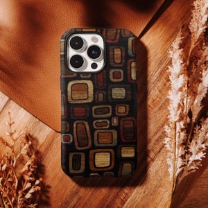 May include: A smartphone case featuring a repeating pattern of rounded rectangles in shades of brown, tan, red, and black. The design covers the back of the device, which has a triple-lens camera module in the upper left corner with a black frame.