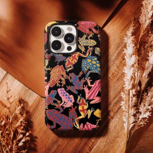 May include: A black smartphone case featuring a repeating pattern of colourful poison dart frogs in shades of red, blue, yellow, and pink. The case has a rectangular camera cutout at the top left corner, revealing three circular camera lenses.