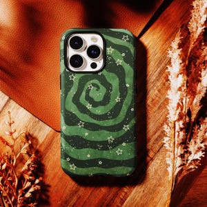 May include: A smartphone case featuring a dark and forest green swirling vortex pattern. The design includes scattered white star outlines and small white dots resembling a starry night sky. The case has a cutout for a triple-lens camera system.