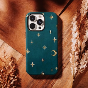 May include: A dark teal phone case featuring a pattern of gold-coloured stars and a crescent moon. The case has a rectangular cutout for a triple-lens camera system on the upper left side, with a black border surrounding the camera lenses.
