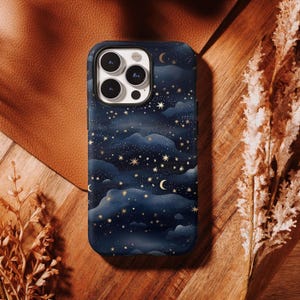 May include: A dark blue smartphone case featuring a celestial pattern of golden stars, crescent moons, and soft, layered clouds. The case has a rectangular cutout for a triple-lens camera system and a flash, covering the back of the device.