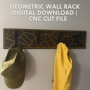 Peut inclure: Porte-manteau mural géométrique en bois marron foncé avec un motif géométrique doré. Il comporte quatre crochets en métal noir et porte une casquette verte et une veste jaune. Le texte sur l'image indique : GEOMETRIC WALL RACK DIGITAL DOWNLOAD | CNC CUT FILE.