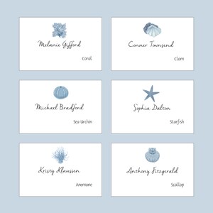 May include: Six place cards with blue watercolor illustrations of sea life and names written in cursive. The illustrations include a coral, a clam, a sea urchin, a starfish, an anemone, and a scallop.