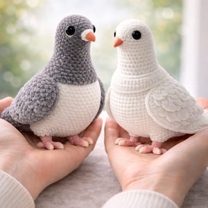 Può includere: Sono esposti due uccelli all'uncinetto fatti a mano, uno grigio e uno bianco. Gli uccelli hanno occhi neri, becchi arancioni e zampe rosa. L'uccello grigio ha la testa e le ali grigie, con il petto bianco. L'uccello bianco è interamente bianco. Gli uccelli sono un affascinante oggetto decorativo.