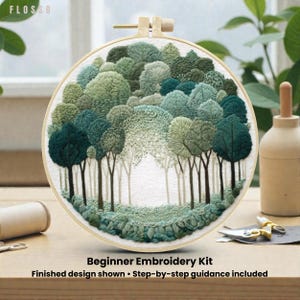 Puede incluir: Un bastidor de bordado con una detallada escena de bosque. El diseño presenta árboles en varios tonos de verde, creando un efecto texturizado y tridimensional. El texto "Beginner Embroidery Kit" es visible. Diseño terminado mostrado. Instrucciones paso a paso incluidas.