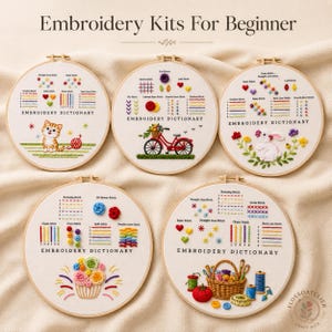 May include: Five embroidery kits for beginners, each in a wooden hoop. The kits feature colorful stitched designs of a cat, a bicycle, a bunny, flowers, and a cupcake. The text "Embroidery Dictionary" is included on each hoop.