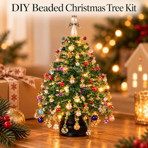 Puede incluir: Un kit de árbol de Navidad de cuentas DIY que presenta un árbol en miniatura de cuentas verdes adornado con cuentas de vidrio multicolores y pequeñas luces blancas cálidas. El árbol está coronado con un ángel de perla blanca sobre una base negra.