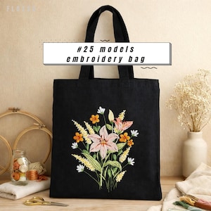 May include: Black tote bag with a floral embroidery design. The embroidery features pink lilies, orange and white flowers, and green leaves. The bag has a rectangular shape and two black handles. Text on the bag reads "#25 models embroidery bag".