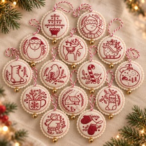 May include: A collection of fourteen circular fabric ornaments featuring red embroidered holiday designs on a cream background. Each ornament has a scalloped edge, a red and white twisted hanging cord, and a small gold bell at the bottom.