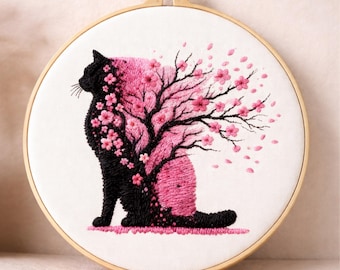 Op de afbeelding: Geborduurd kunstwerk van een zwarte kat met een roze kersenbloesemboomontwerp. De kat zit, met de takken en bloemen van de boom die omhoog uitsteken. De borduursel is geplaatst in een houten hoepel, met de tekst "FlossoAtelier" bovenaan.