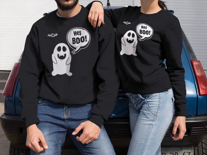 May include: A black sweatshirt with a white ghost graphic and the text "Hey Boo!" printed on it. The sweatshirt is being worn by a person.