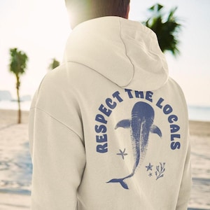 May include: A cream-coloured hoodie with a blue whale graphic and the text "Respect the Locals" on the back.