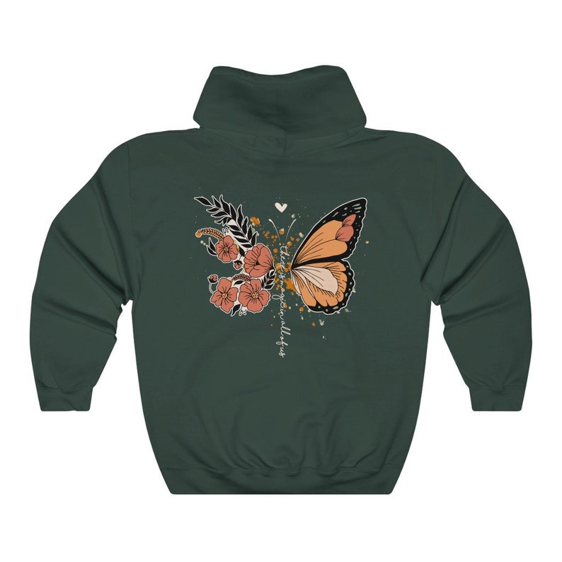 May include: A dark green hooded sweatshirt featuring a butterfly and floral design on the back. The butterfly is orange and black, with peach-colored flowers and the text "there is magic in all of us".