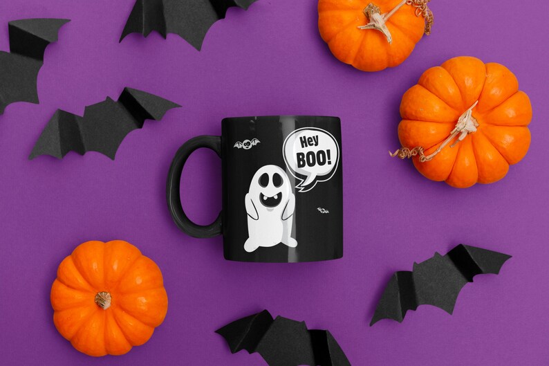 May include: A black coffee mug with a white ghost and the text "Hey BOO!" on a purple background with orange pumpkins and black bats.