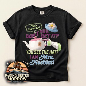 May include: Black t-shirt with a graphic featuring a teapot, a blue hat with a flower, and text that reads "Ohhh Hannahh! DON'T YOU GET IT? YOU SEE THE HAT? I AM Mrs. Nesbitt!" The shirt also has a logo that says "Paging Sister Morrow Design Co."