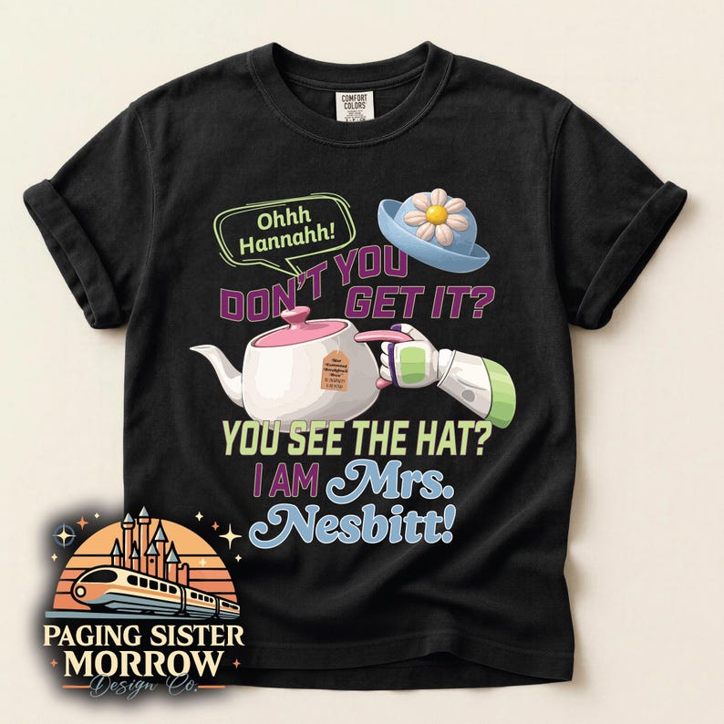 May include: Black t-shirt with a graphic featuring a teapot, a blue hat with a flower, and text that reads "Ohhh Hannahh! DON'T YOU GET IT? YOU SEE THE HAT? I AM Mrs. Nesbitt!" The shirt also has a logo that says "Paging Sister Morrow Design Co."