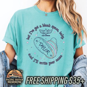 May include: A teal short-sleeve t-shirt featuring a graphic of a space ranger boot with the name TAYLOR written on the sole. The text reads but I've got a blank space, baby, and I'll write your name, along with a Star Command logo and small stars.