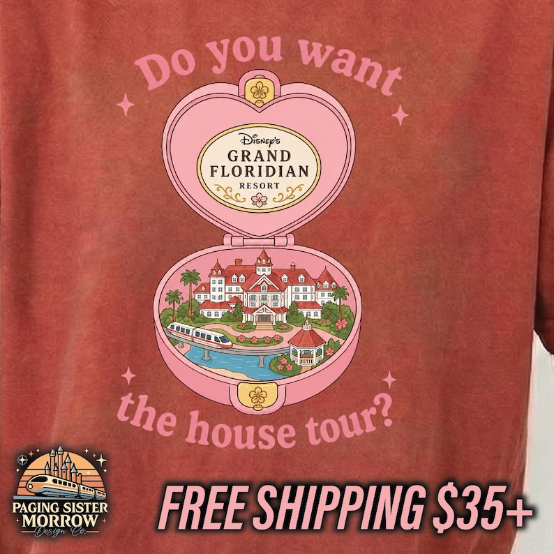 Puede incluir: Una camiseta color rojo ladrillo con un gr&aacute;fico de un estuche compacto rosa en forma de coraz&oacute;n. Dentro hay una ilustraci&oacute;n del Disney Grand Floridian Resort con un monorra&iacute;l. El texto dice: Do you want the house tour? y Disney's Grand Floridian Resort.