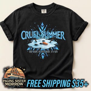 May include: Black t-shirt with a graphic that reads "CRUEL SUMMER" in blue, featuring a melting snowman scene. The text "THE SHAPE OF YOUR BODY. IT'S NEW" is below the graphic. The shirt has rolled-up sleeves.