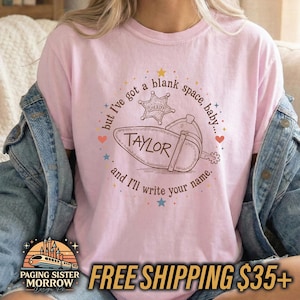 Peut inclure: Un t-shirt rose clair avec une impression graphique marron repr&eacute;sentant une botte de cow-boy et une &eacute;toile de sh&eacute;rif. Le texte indique, but I've got a blank space, baby... and I'll write your name. Le mot TAYLOR est imprim&eacute; sur la botte.