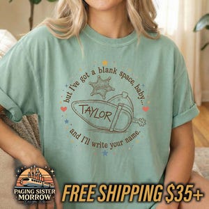 Peut inclure: Un t-shirt &agrave; manches courtes vert sauge avec une impression graphique marron repr&eacute;sentant une botte de cowboy, une &eacute;toile de sh&eacute;rif et le texte : but I've got a blank space, baby... TAYLOR and I'll write your name, entour&eacute; de petites &eacute;toiles.