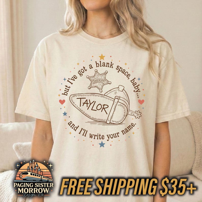 Peut inclure: Un t-shirt &agrave; manches courtes de couleur cr&egrave;me avec une impression graphique marron. Le motif comprend une &eacute;toile de sh&eacute;rif, une botte de cow-boy et le texte : but I've got a blank space, baby... TAYLOR and I'll write your name. Des &eacute;toiles et des c&oelig;urs entourent le texte.