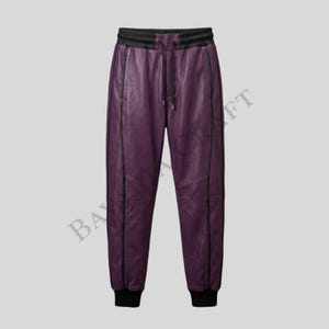 May include: Purple leather joggers with black trim and a drawstring waist. The pants have a black elastic waistband and cuffs. The image shows the pants against a light gray background.